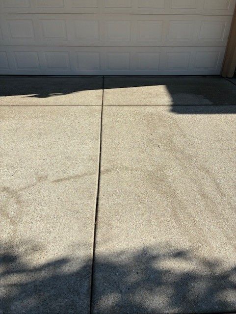 Cleanup King LLC - Concrete driveway with a vertical crack in front of a closed garage door.