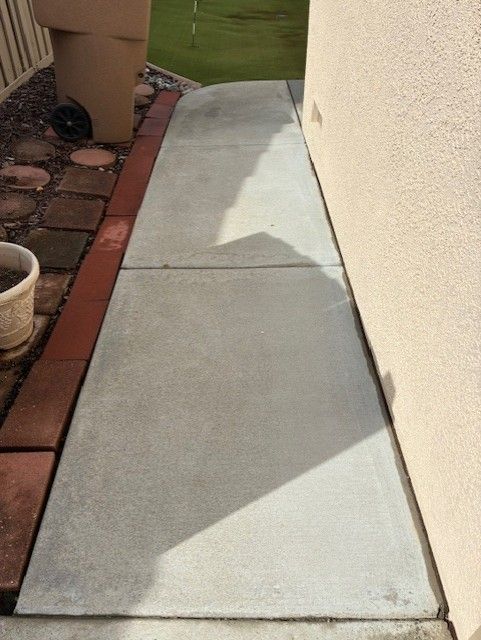 Cleanup King LLC - Concrete walkway next to a stucco wall, bordered by bricks.