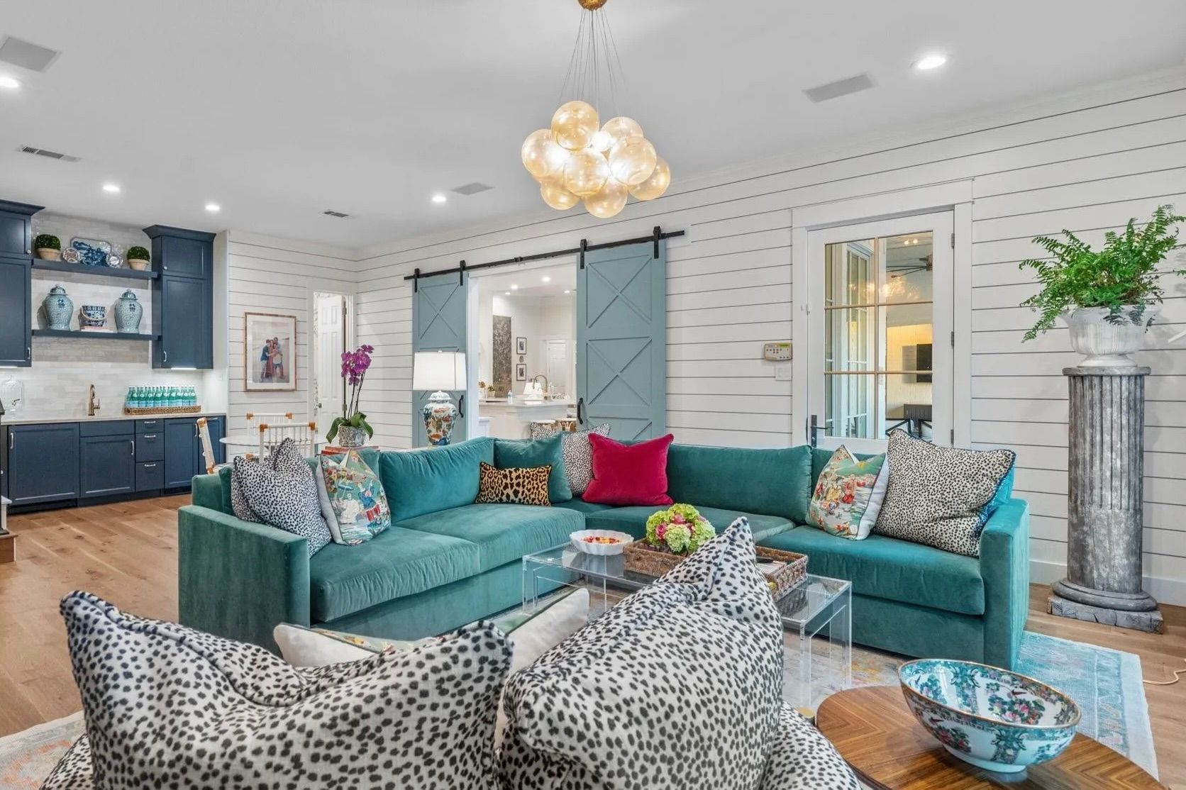 Living room transformation in Keller, Texas, featuring shiplap walls, custom barn doors, new flooring, upgraded lighting, and custom cabinets by Night 'N' Day Construction.