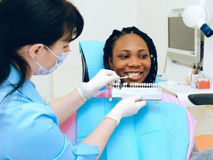 girl smiling while dental assistant reviews the teeth color pallet options for cosmetic dentistry