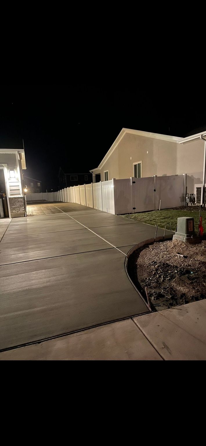 Nighttime suburban street with lit houses, a driveway, and a trash bin by the curb. Nighttime suburban street with lit houses, a driveway, and a trash bin by the curb.