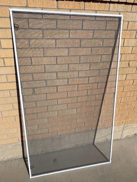 A mosquito screen is sitting in front of a brick wall