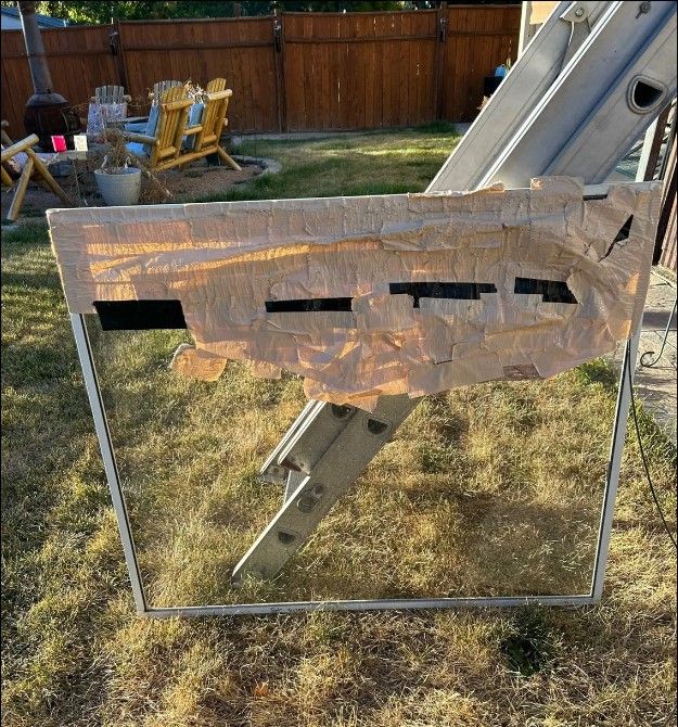 A ladder is sitting in the grass in front of a wooden fence