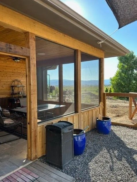 A screened in porch with a trash can and blue pots