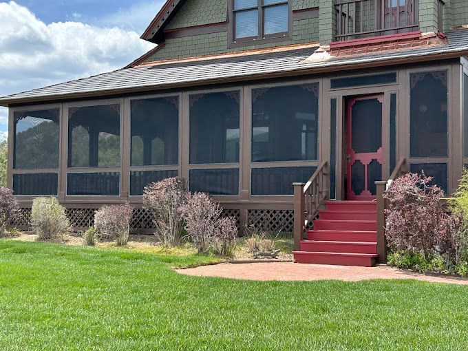 A house with a screened in porch and red stairs.