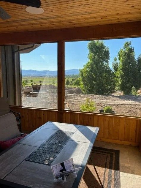A room with a table and a large window with a view of a field.
