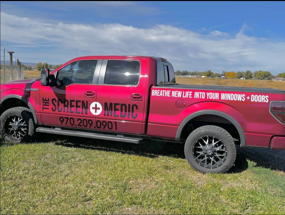 A red truck is parked in a grassy field.