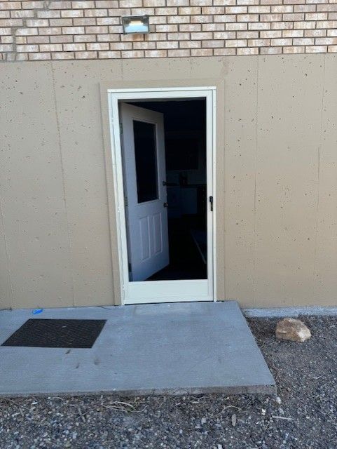 A white door is open to a brick building