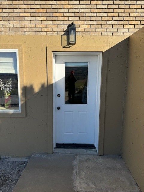 A white door with a window on the side of a brick building