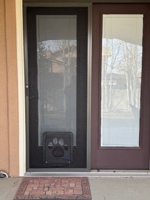 A brown door with a screen door and a paw print door.