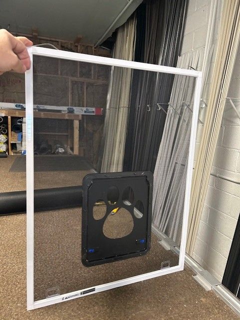 A person is holding a screen door with a paw print on it.