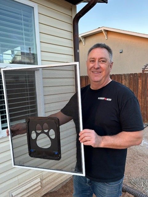 A man is holding a screen door in front of a house.
