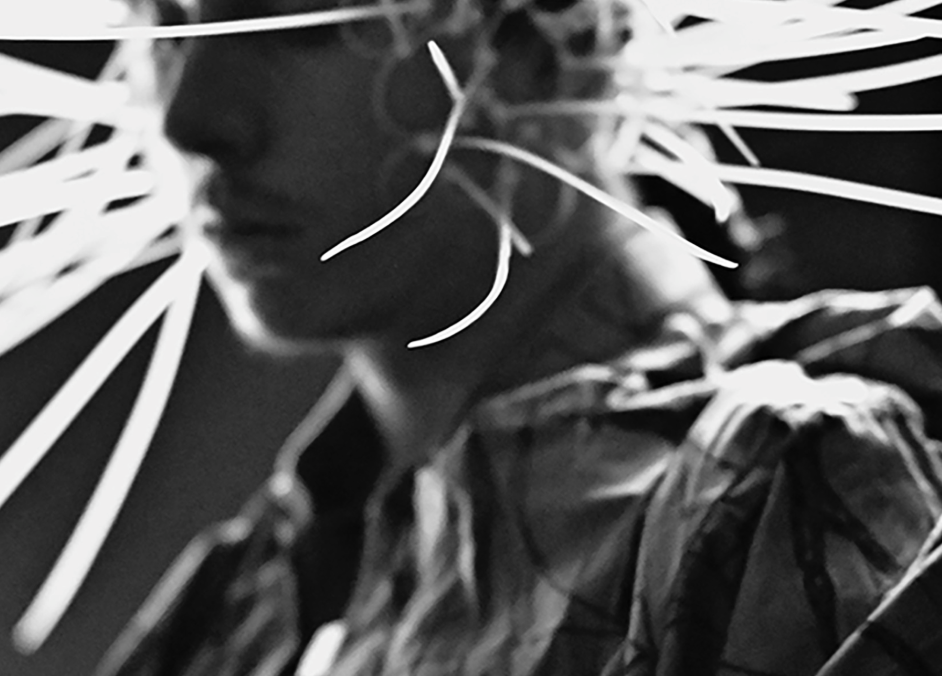 Black and white photo of person, light streaks surrounding head. Focus on profile, wearing patterned shirt.