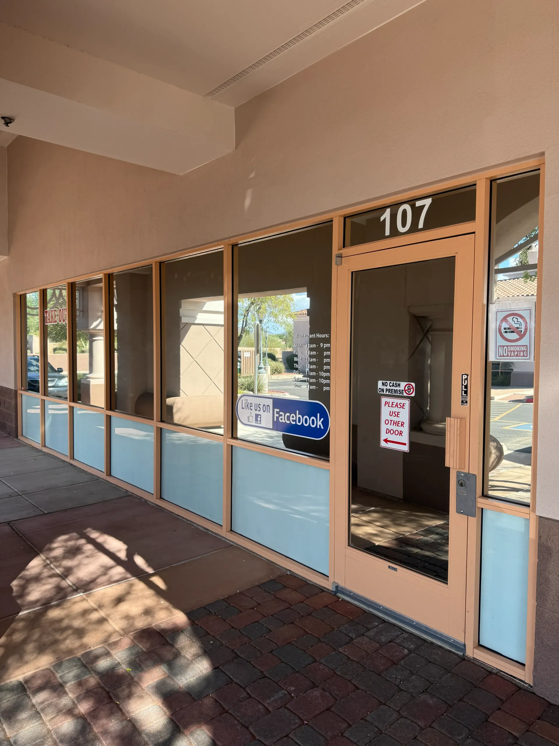 Exterior of commercial space, number 107. Beige door and window frames, frosted lower windows.