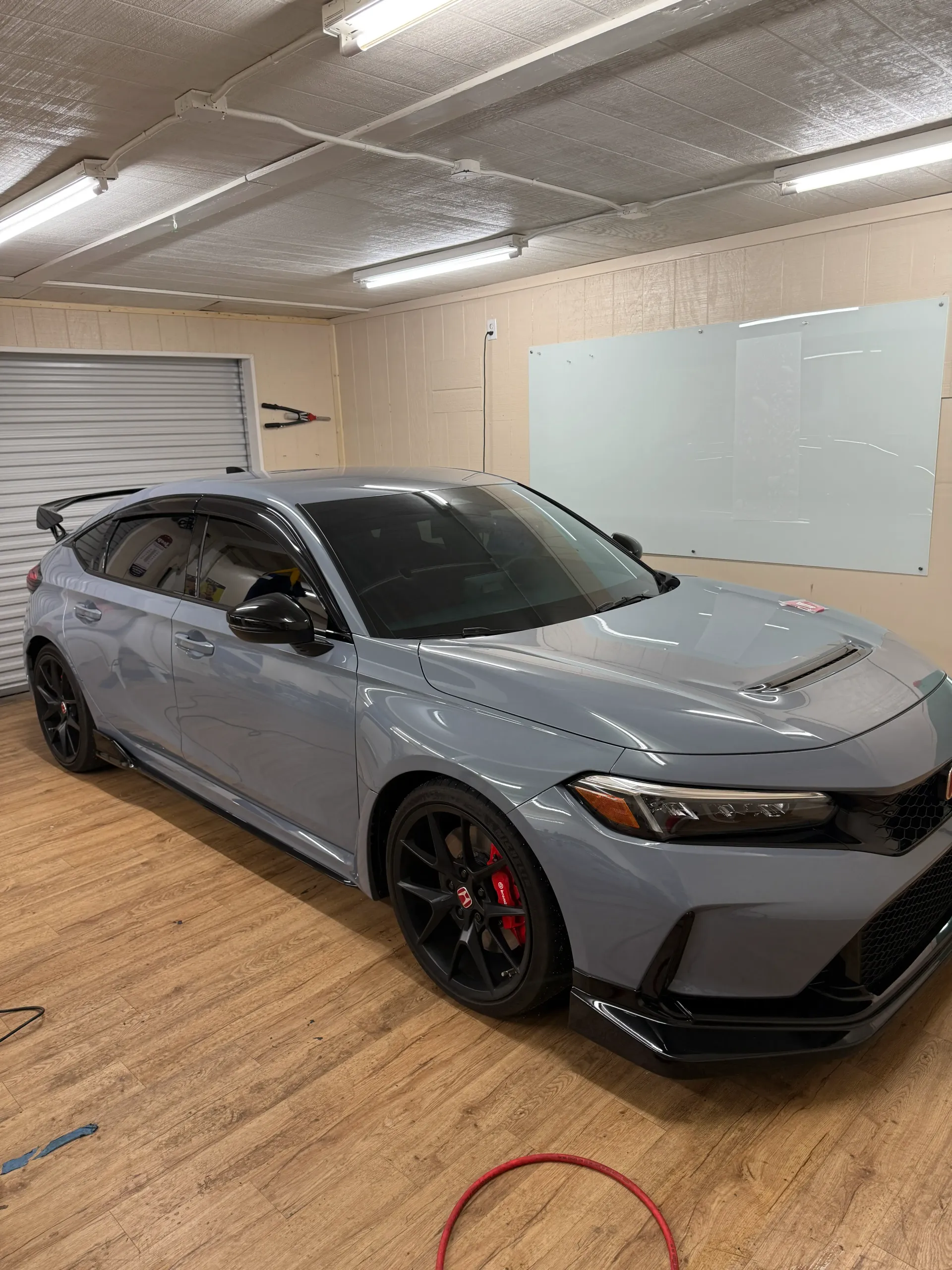 Gray Honda Civic Type R parked indoors, with tinted windows and black accents, red brake calipers.
