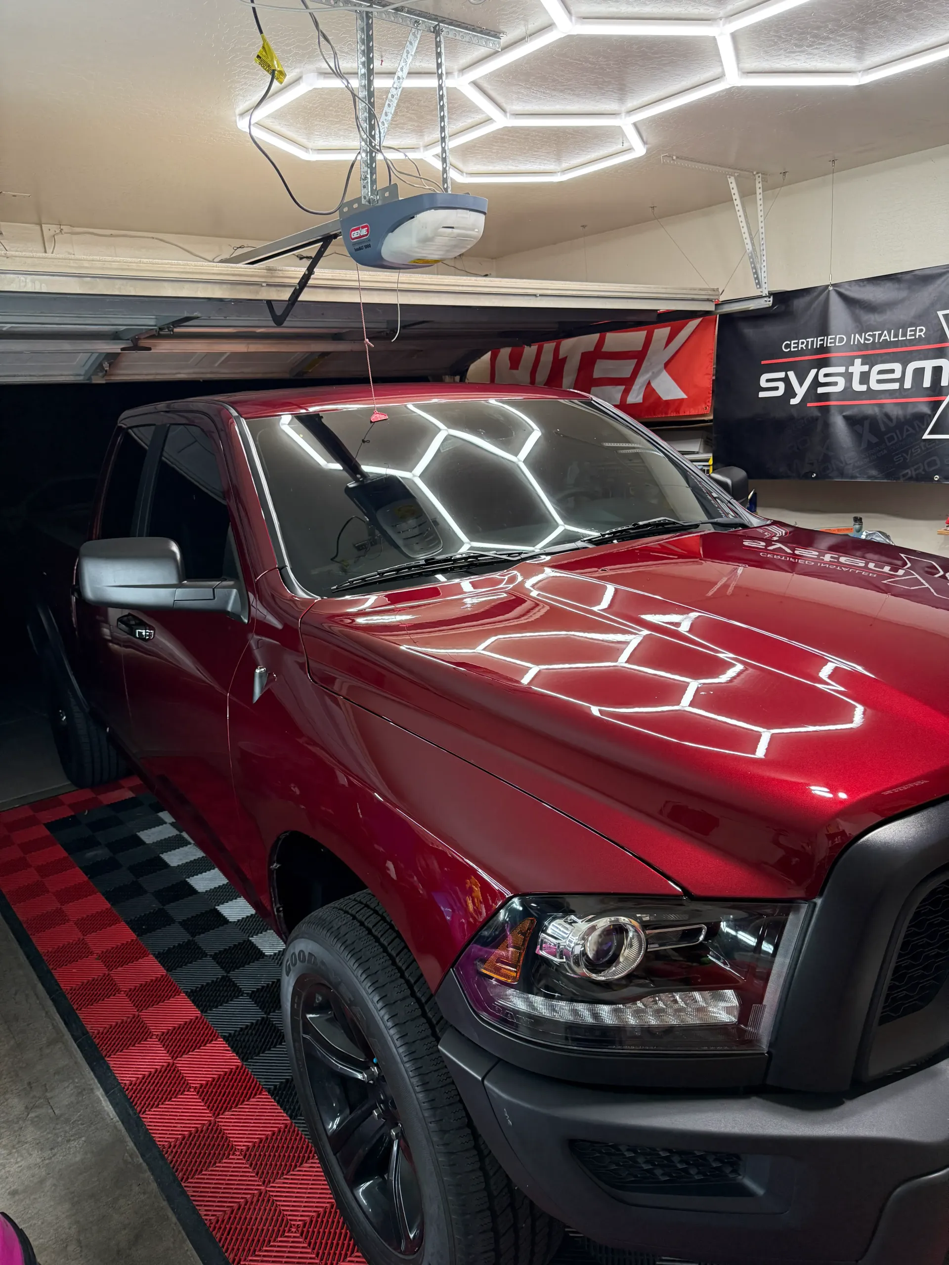 Red pickup truck parked in a garage with honeycomb-shaped lights on the ceiling.
