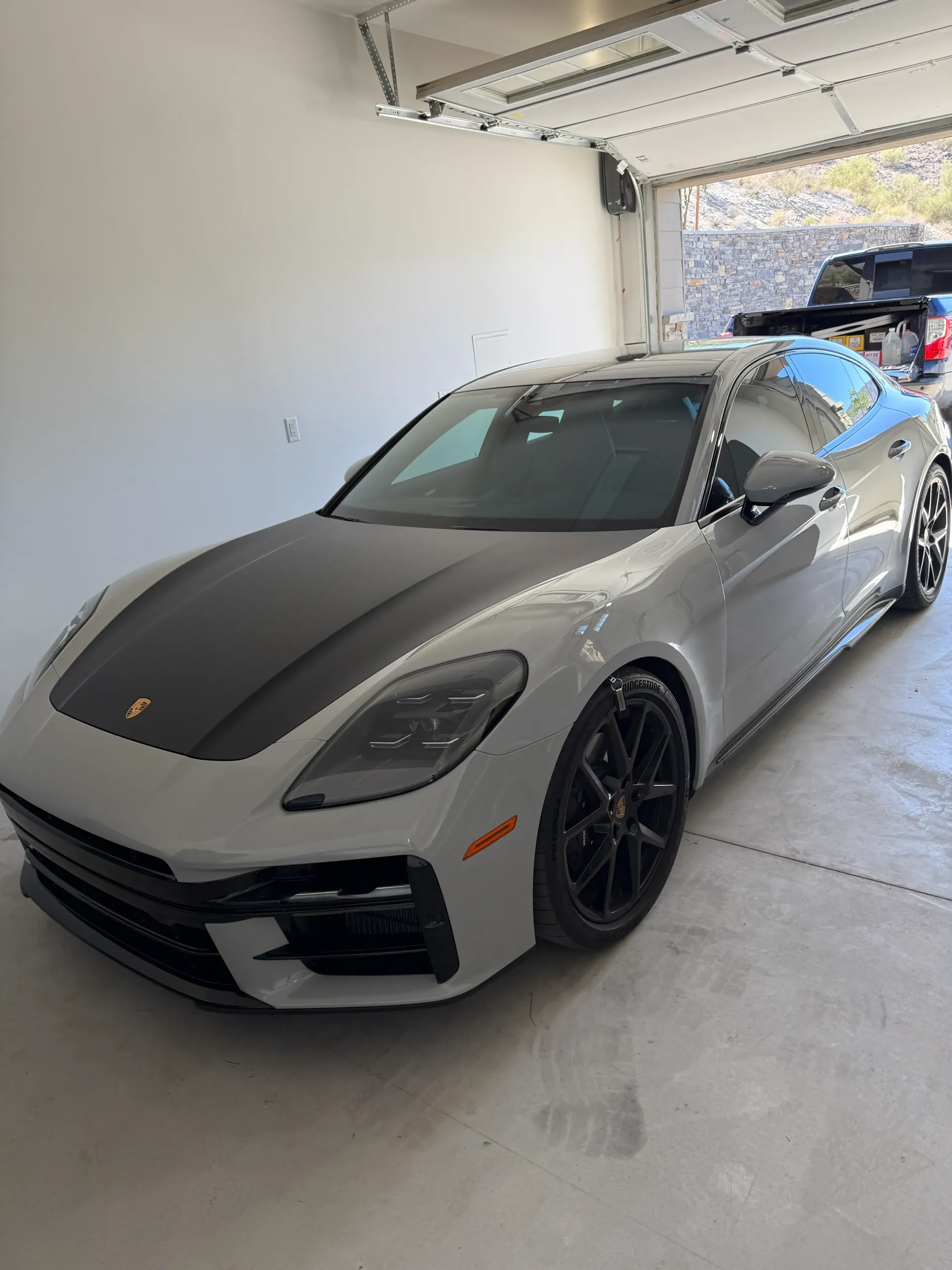 Gray Porsche Panamera with black hood in a garage.