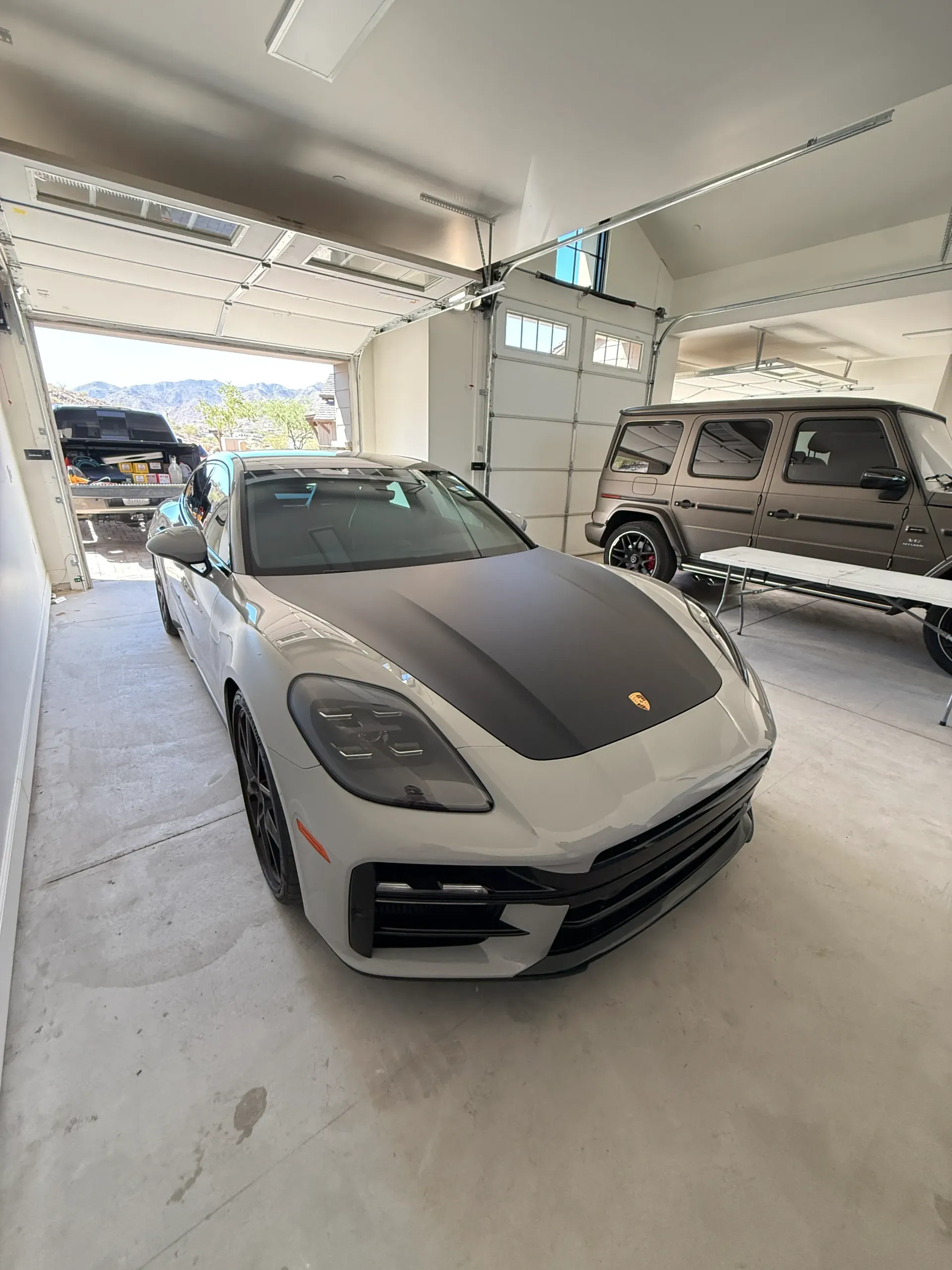 Silver Porsche and brown SUV parked inside a garage.