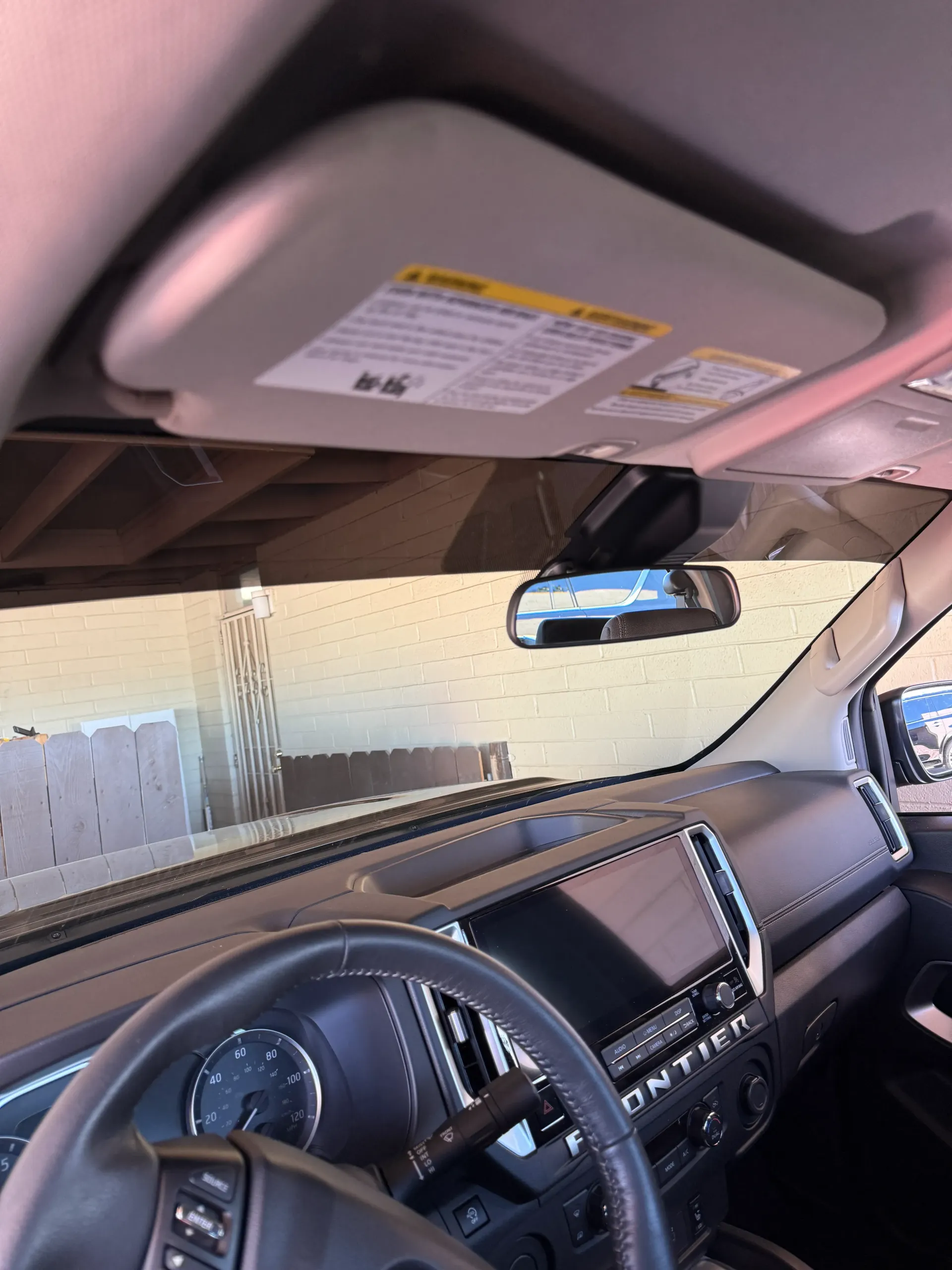 Interior view of a car with a dashboard, steering wheel, and sun visor.