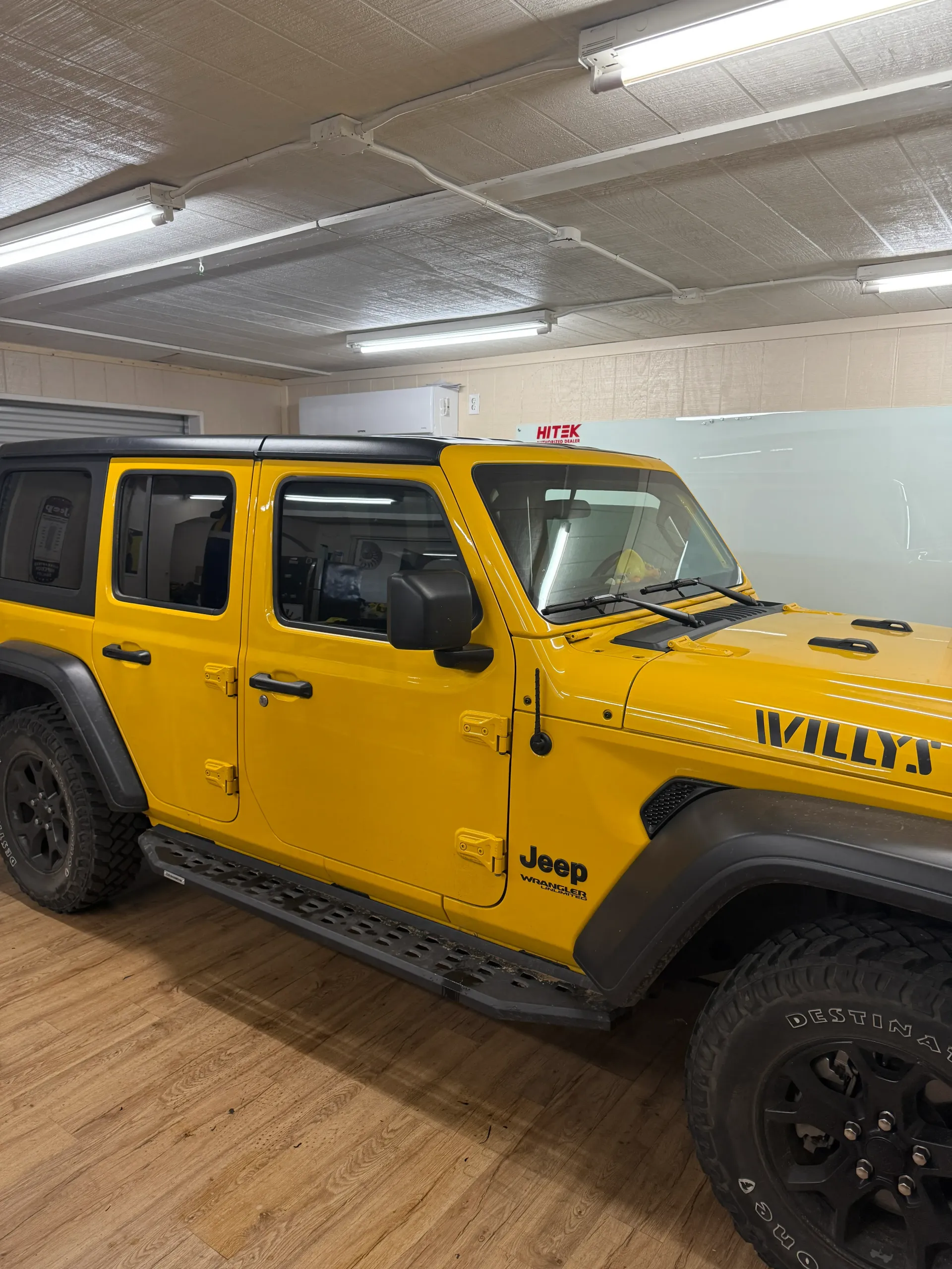 Yellow Jeep Wrangler Willys parked indoors.