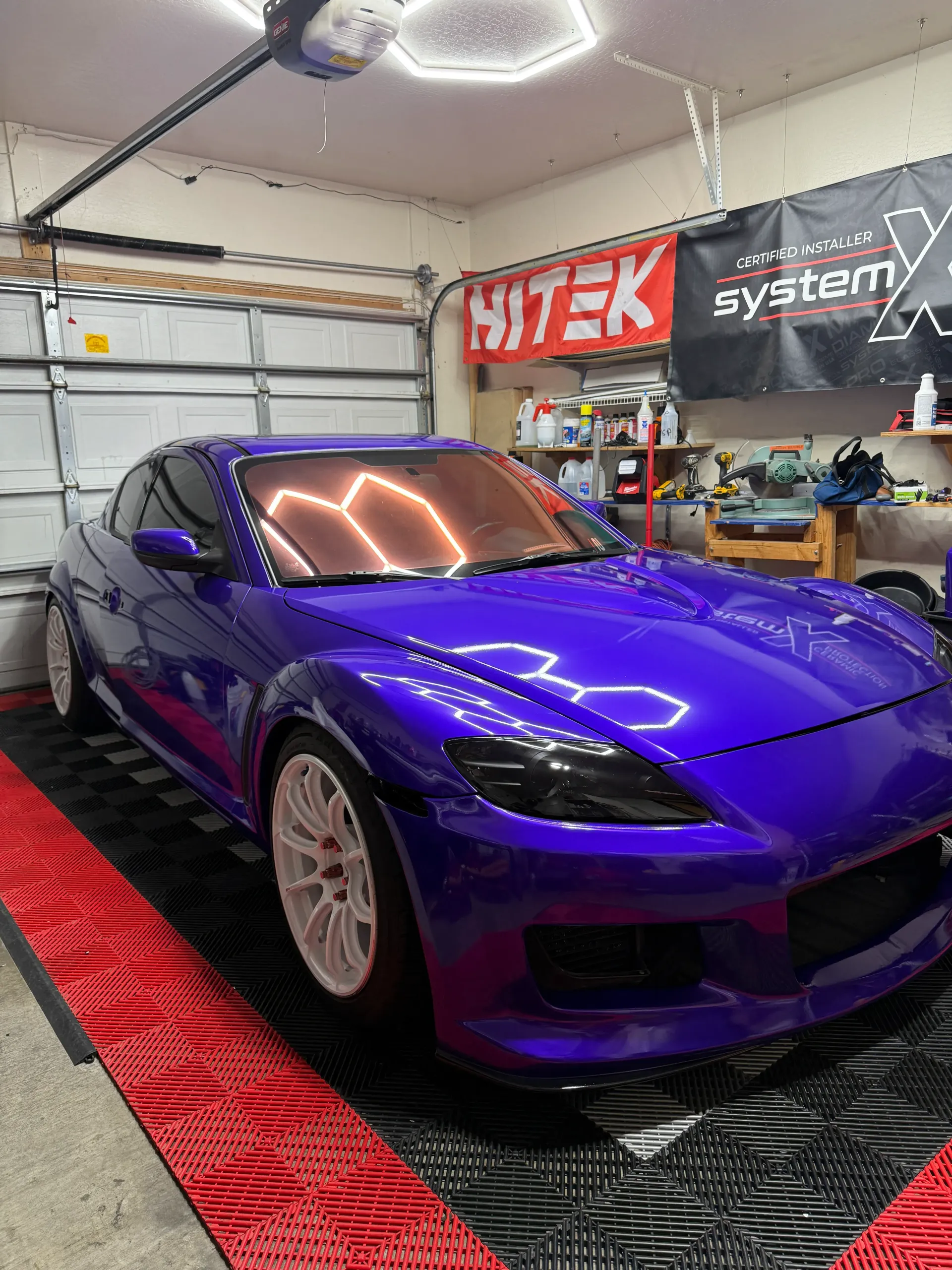 Purple sports car in a garage with red and black flooring.