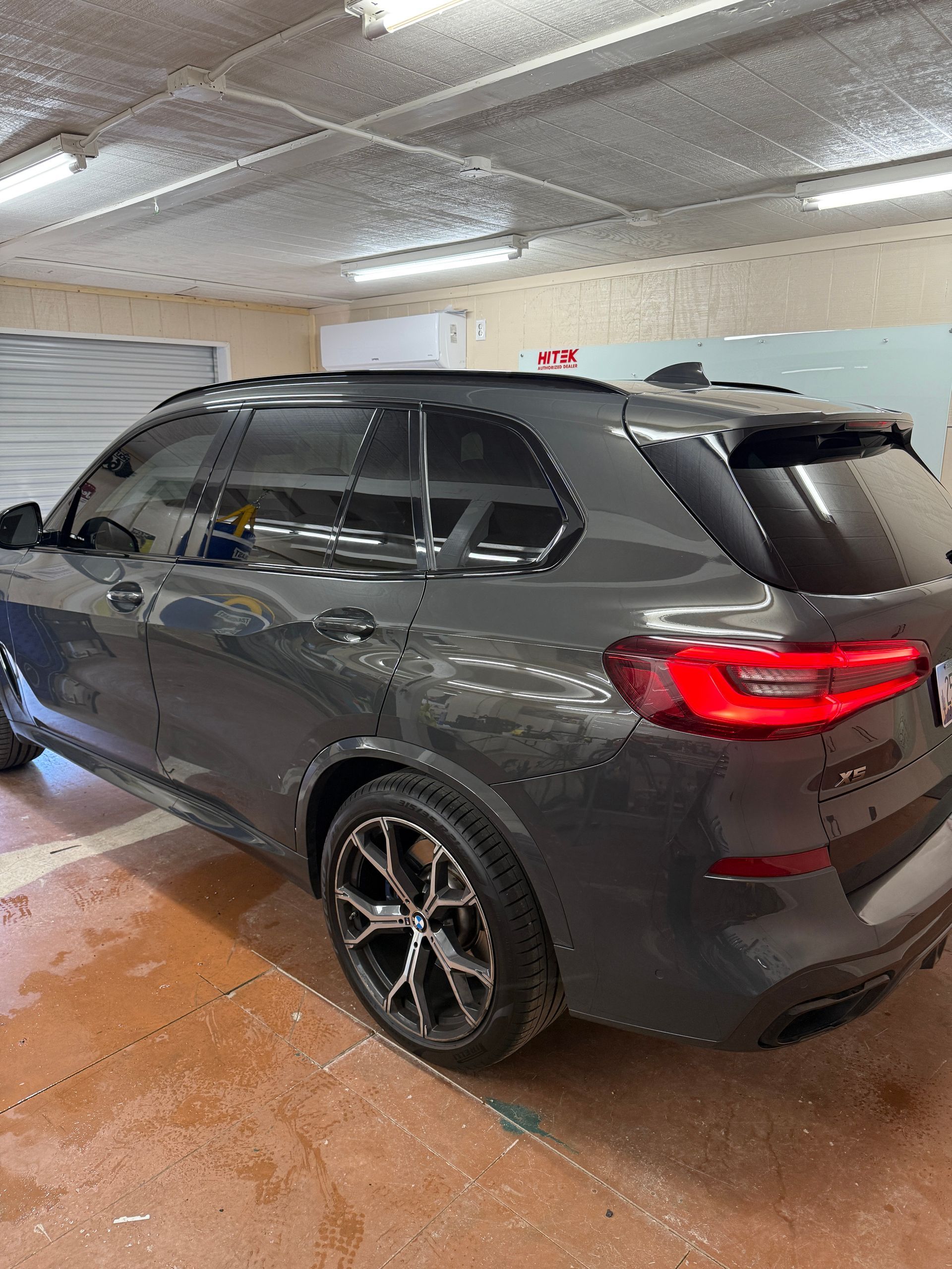 Gray BMW SUV parked inside a garage, tinted windows.