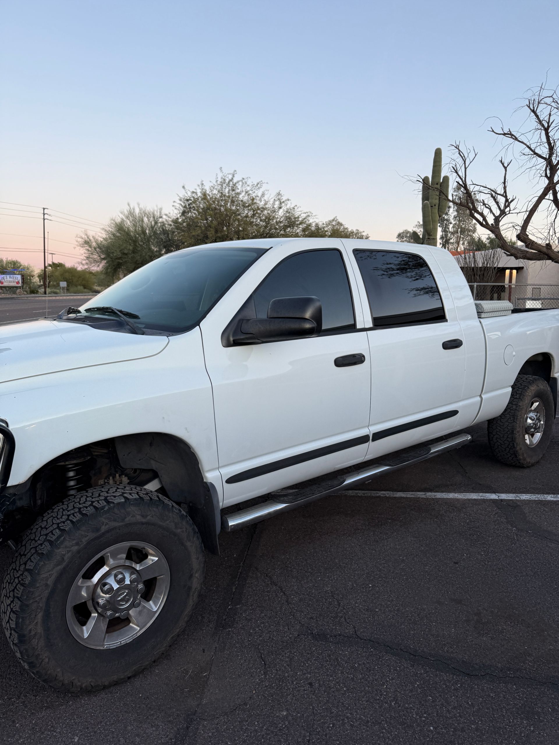 White Dodge Ram pickup truck parked outdoors near desert vegetation.