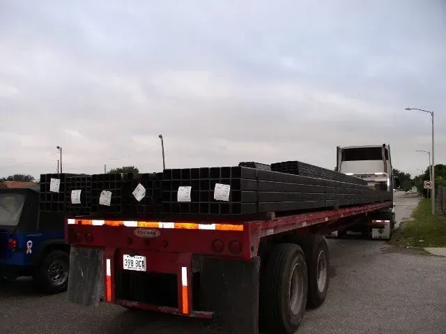 A red semi truck is carrying a stack of black squares.