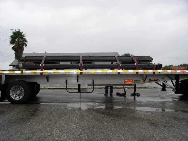 A trailer with a lot of pipes on it.