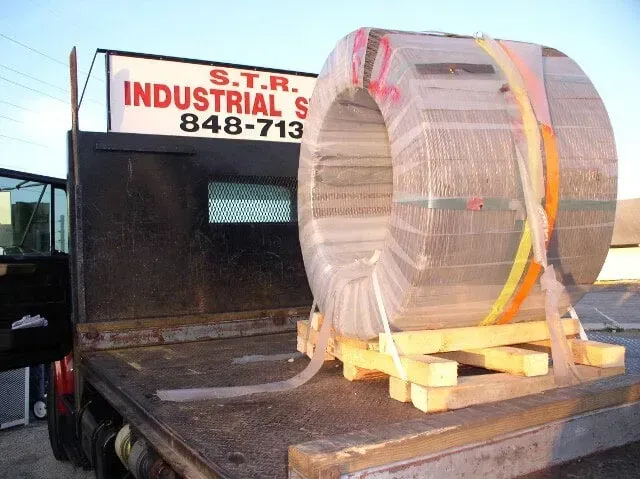 A truck with a large spool of metal on the back.