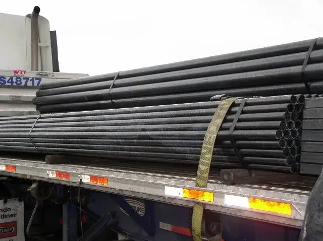 A truck with a bunch of pipes on the back of it.