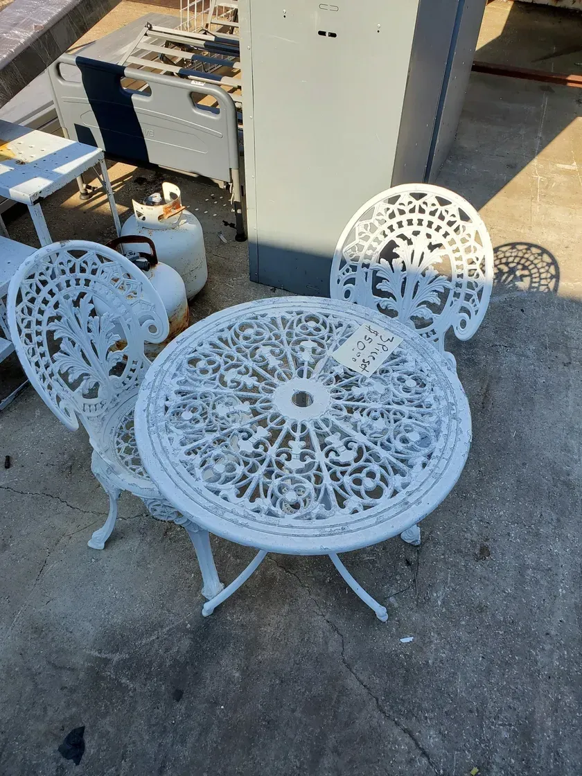 A white table and chairs are sitting on the ground.