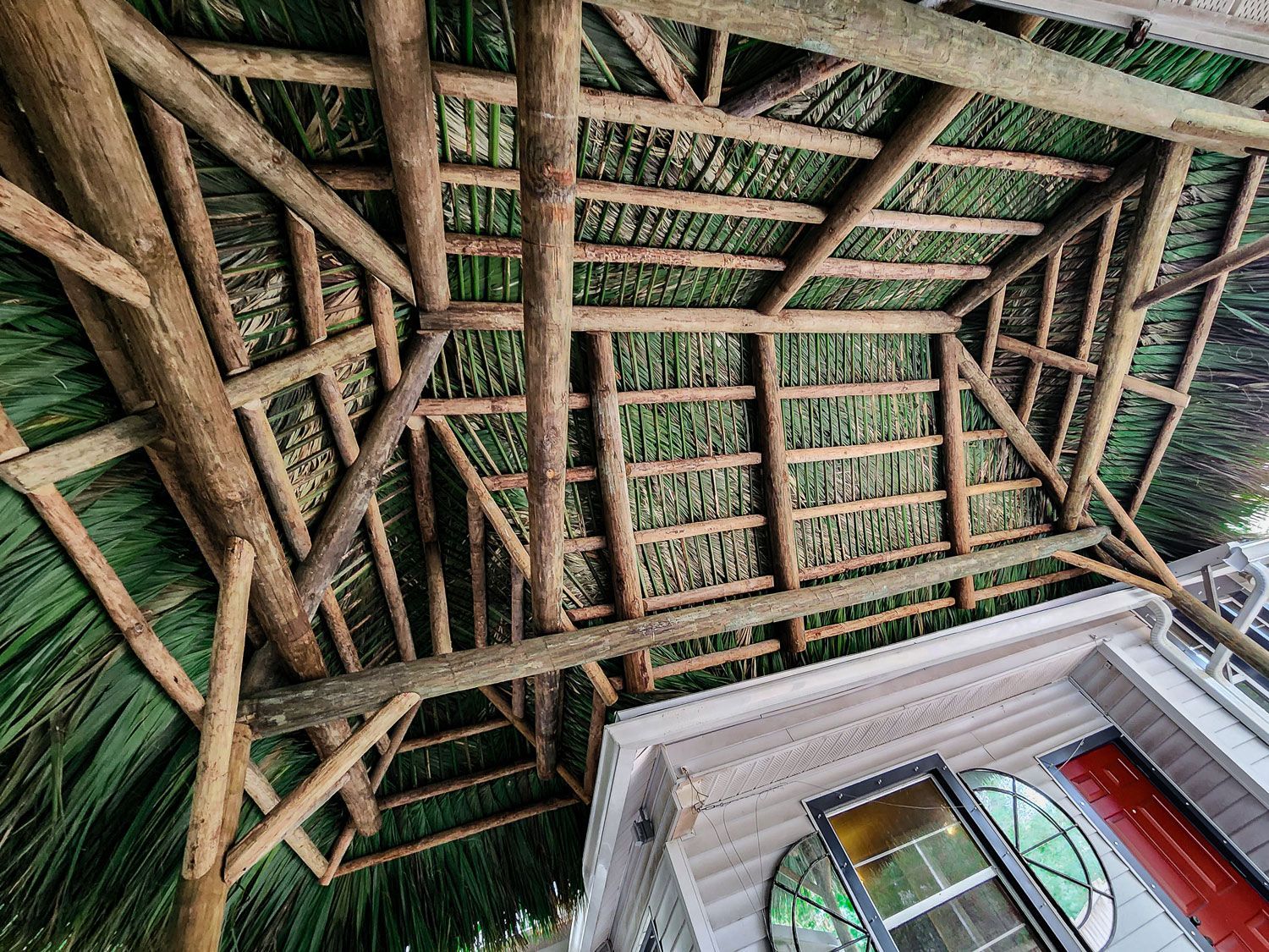 Wooden thatched roof over a building's porch, green and brown hues.
