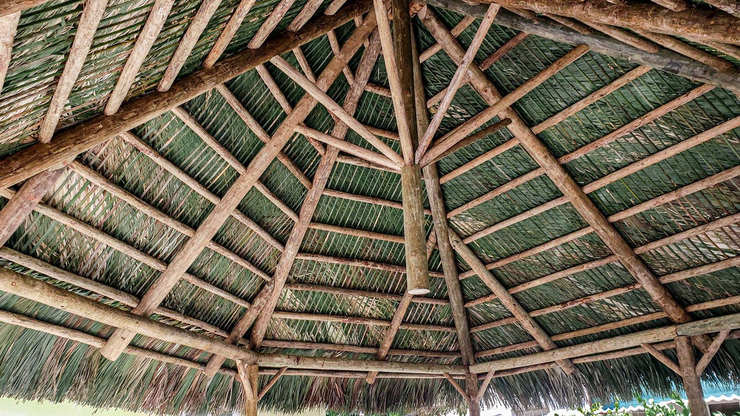 Wooden gazebo roof with a layered green thatched roof.