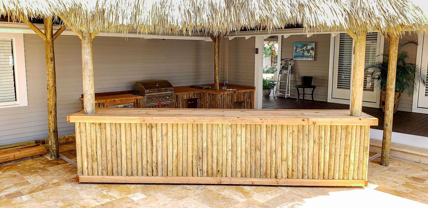 Outdoor bar with bamboo facade, thatch roof, and wooden posts.