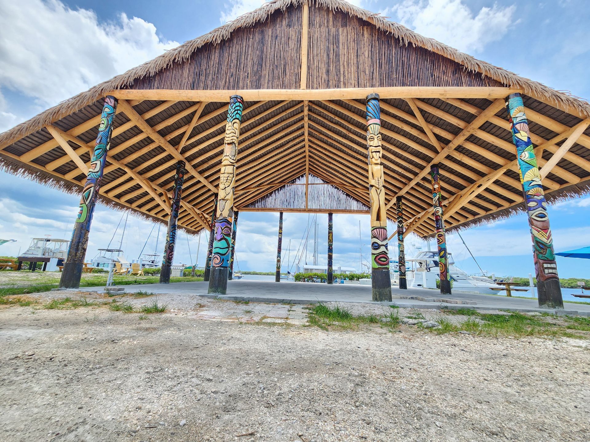 Looking up at a thatched-roof umbrella against a clear blue sky.