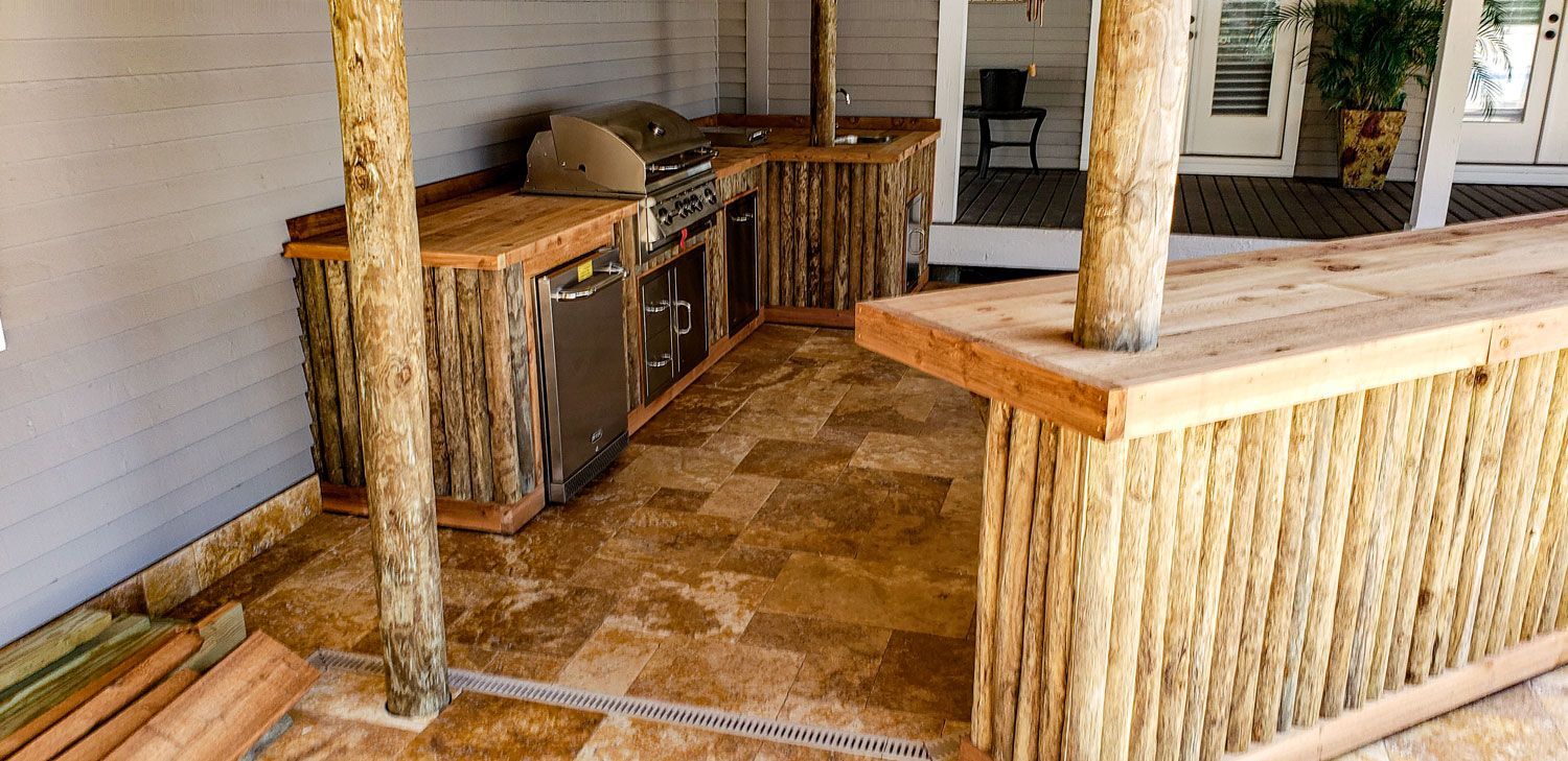 Outdoor kitchen with natural wood cabinetry and a bar.