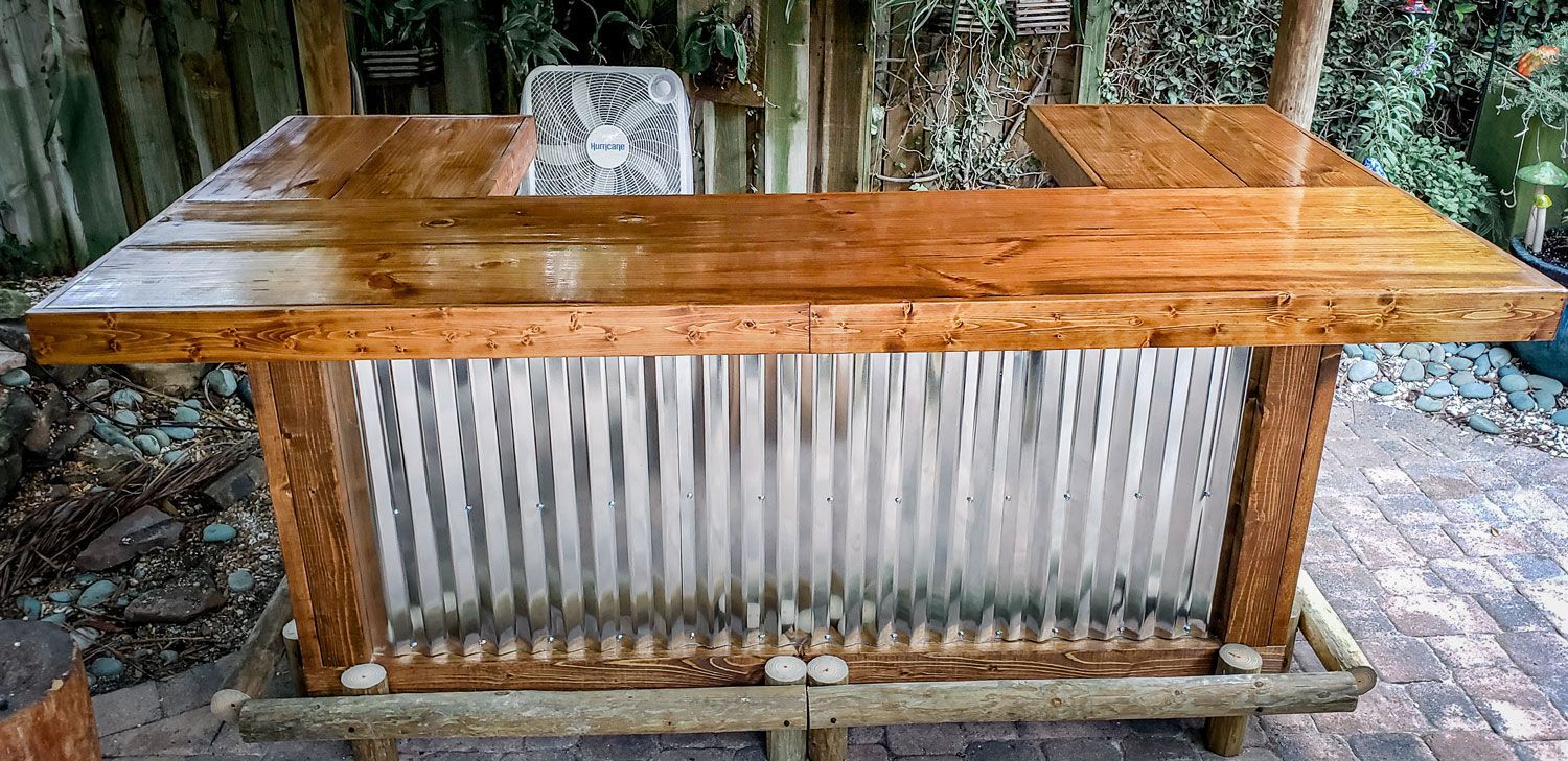 Wooden outdoor bar with corrugated metal front and wood countertops.