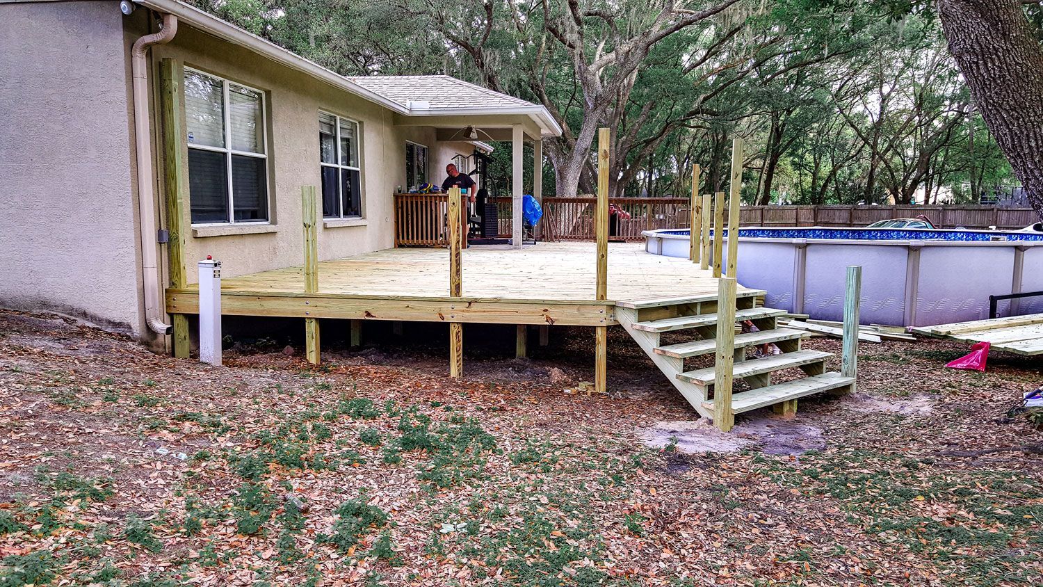 Wooden deck attached to a house, with stairs leading down to an above-ground pool. Wooden deck attached to a house, with stairs leading down to an above-ground pool.