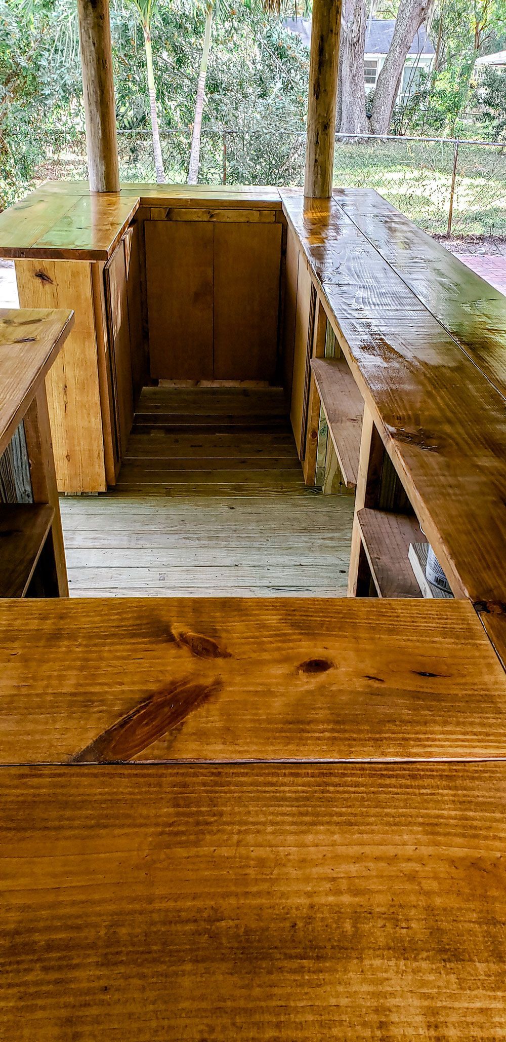 Wooden outdoor bar structure with a natural forest background.