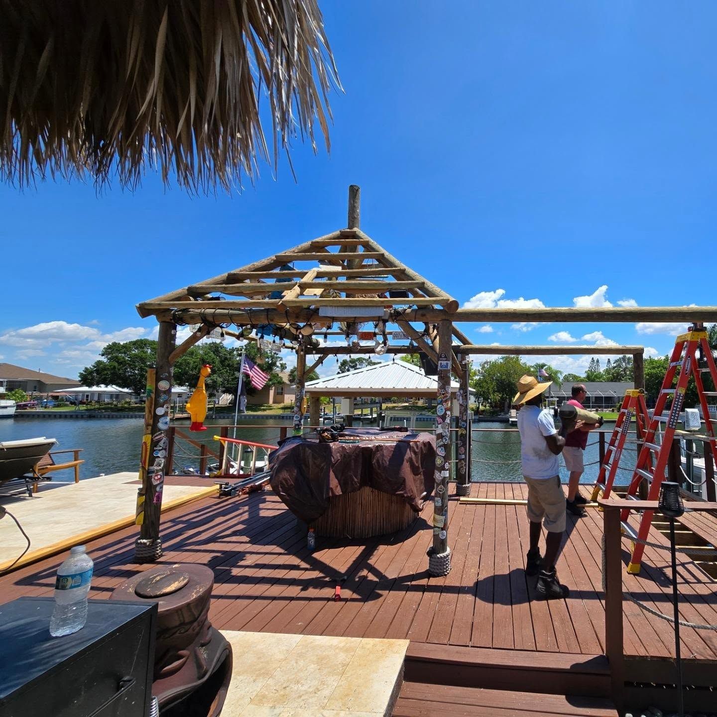 Wooden dock with tiki hut and workers on a sunny day. Wooden dock with tiki hut and workers on a sunny day.