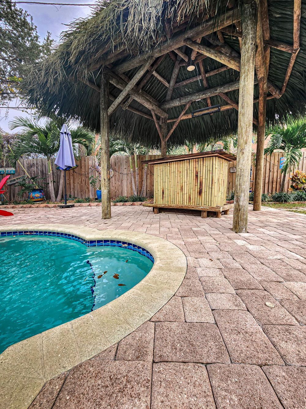 Poolside thatched roof structure with a small wooden bar and heart-shaped pool.
