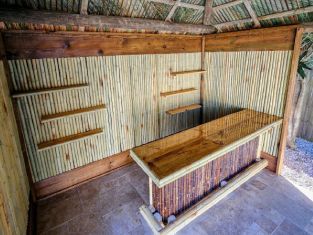 Wooden tiki bar with bamboo paneling and shelves. Palm thatch roof. Wooden tiki bar with bamboo paneling and shelves. Palm thatch roof.