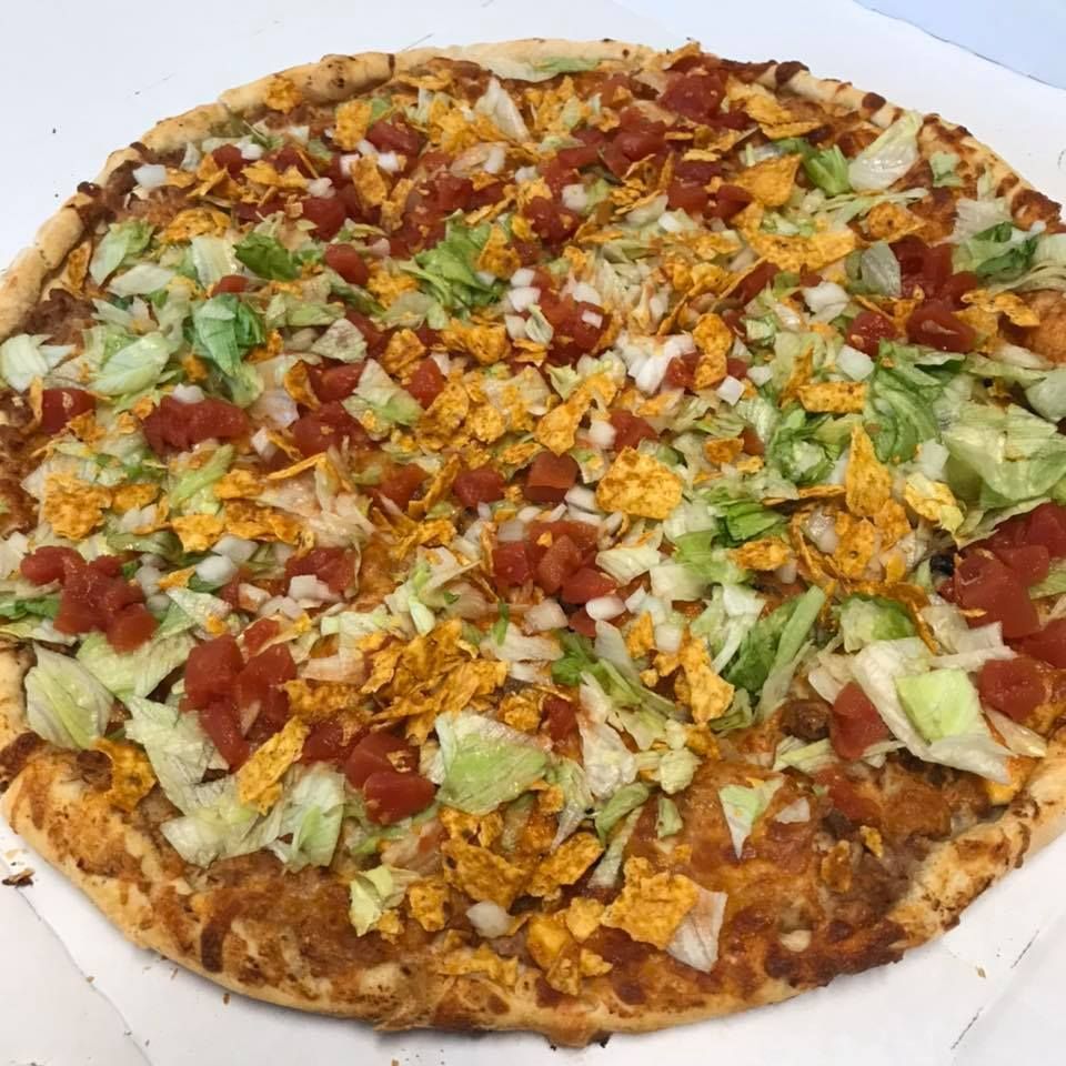 Taco pizza: round crust topped with lettuce, tomatoes, onions, and crushed chips.