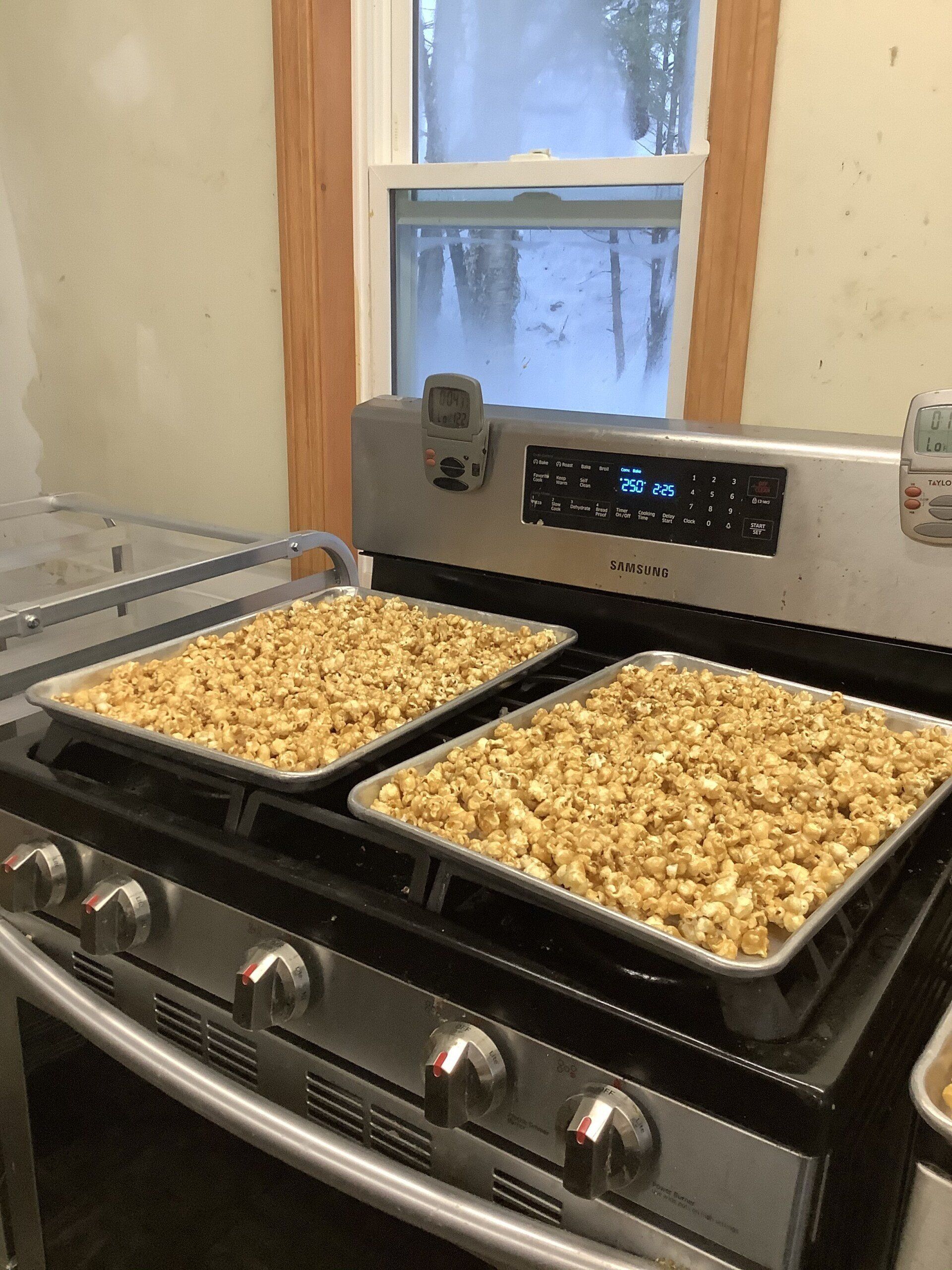 two trays of popcorn sitting on a stove top