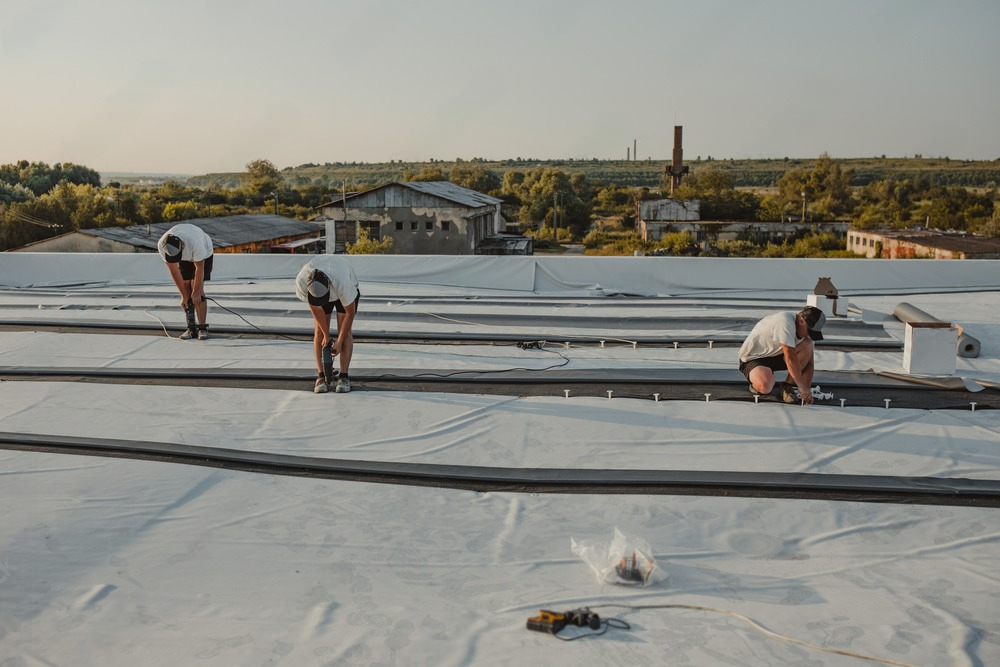 three men are working on a white roof