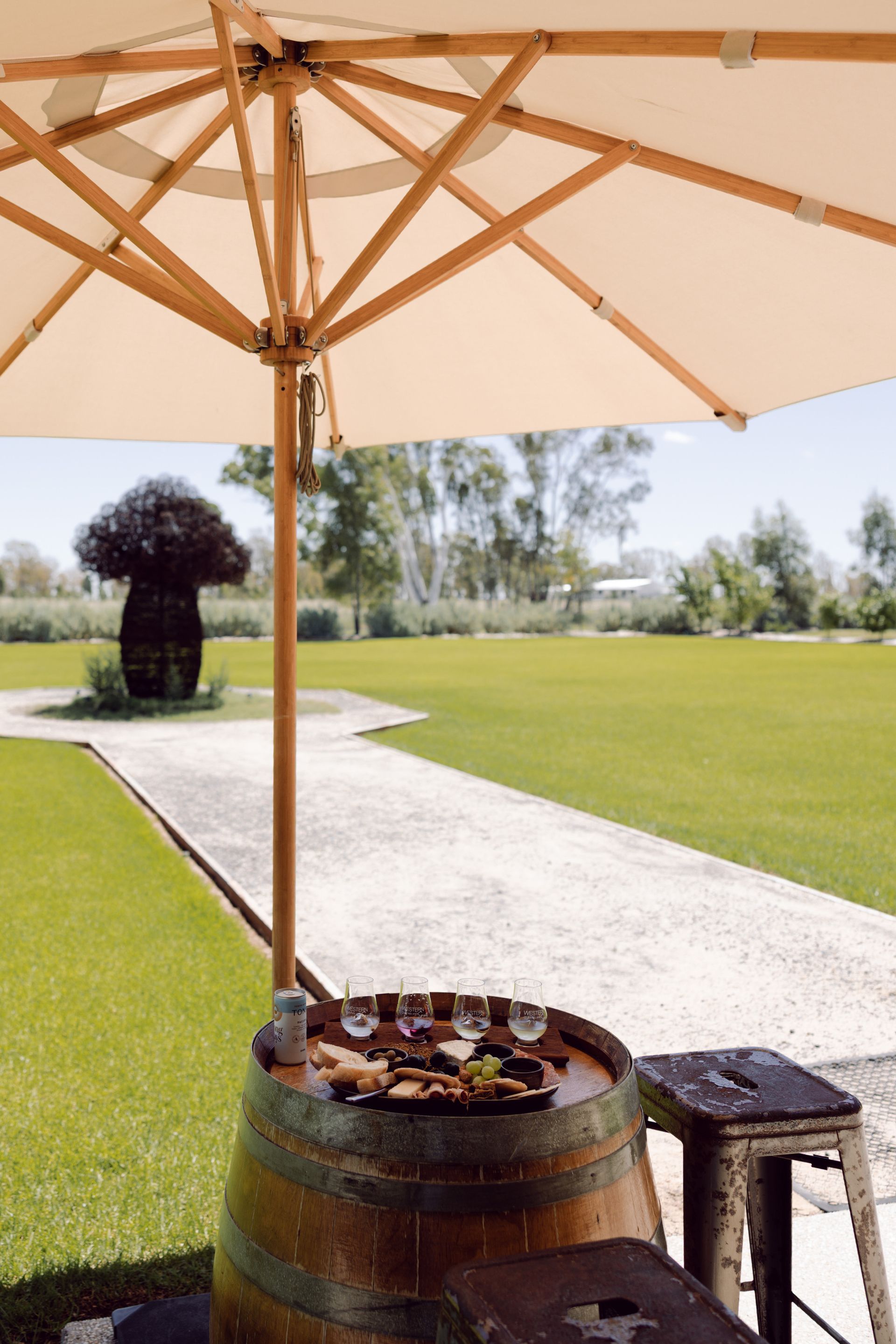 Australian distillery tasting experience in Roma, Queensland, with glasses and grazing platter on barrel in outdoor setting.