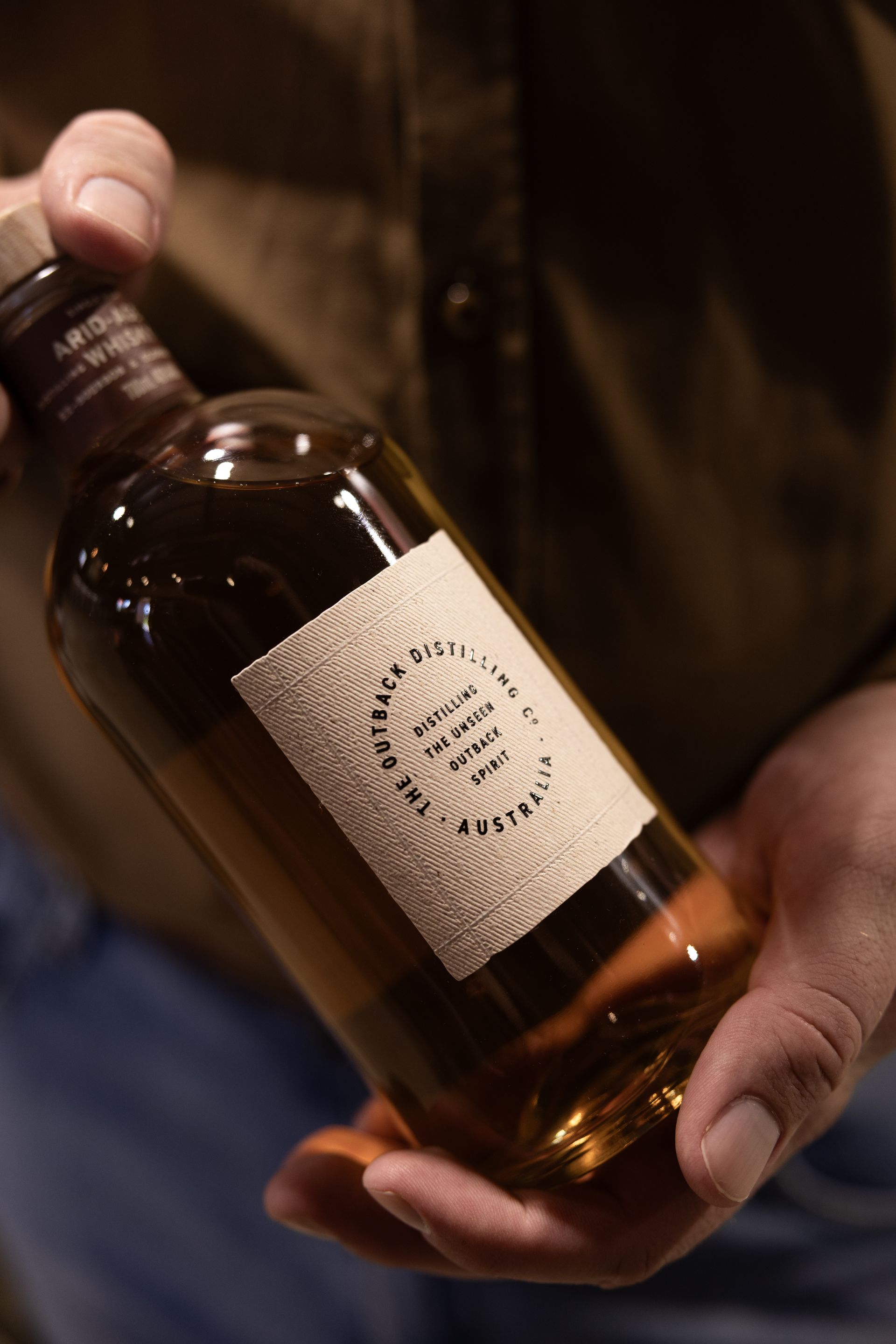 Australian single malt whisky by The Outback Distilling Co held in hand, showing label and spirit.