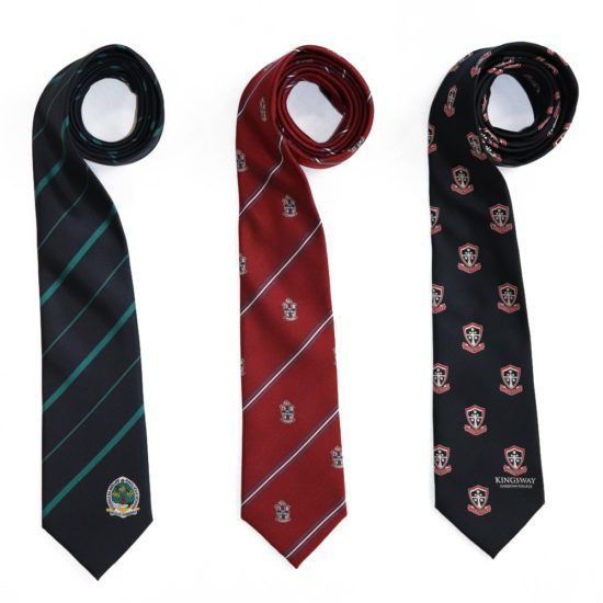 Three rolled neckties: black with green stripes, maroon with white stripes, and black with repeating crest pattern.