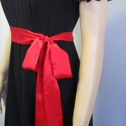Black dress with a red satin sash tied in a bow at the waist.